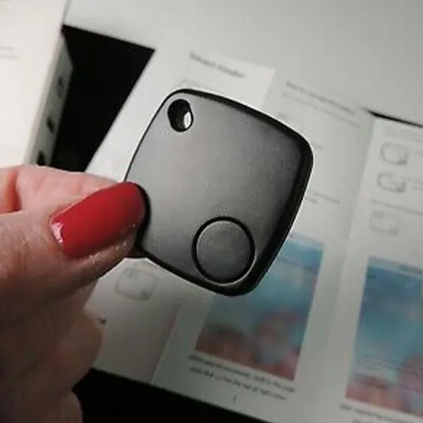 iTagPro Bluetooth tracker held in hand next to a phone showing the tracking app